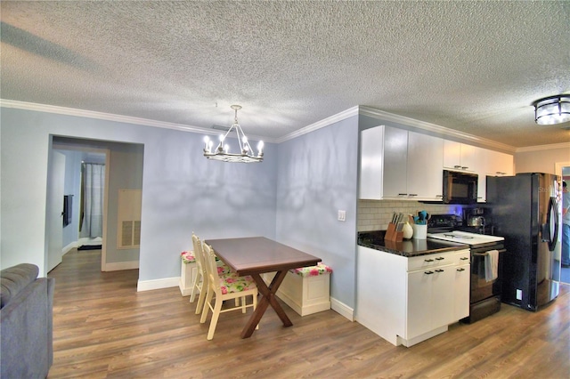 kitchen featuring white cabinetry, hanging light fixtures, a notable chandelier, black appliances, and ornamental molding