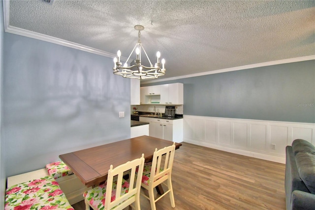 dining space with a chandelier, wood-type flooring, a textured ceiling, and crown molding