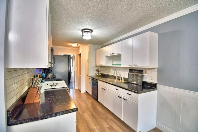 kitchen featuring white cabinets, ornamental molding, dishwasher, and sink