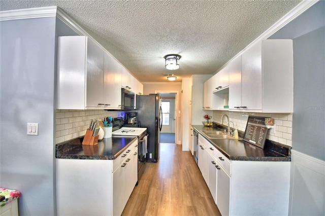 kitchen with decorative backsplash, sink, white cabinetry, and black appliances