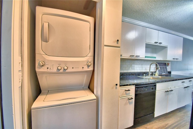 laundry area with hardwood / wood-style flooring, stacked washer / drying machine, and sink