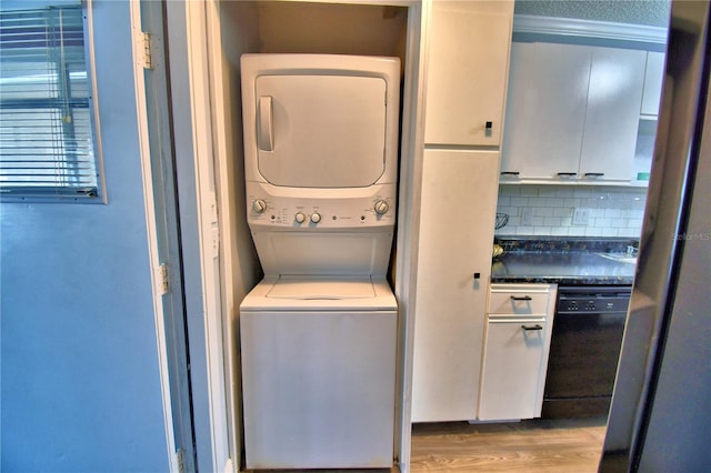 clothes washing area with light hardwood / wood-style floors and stacked washer and clothes dryer