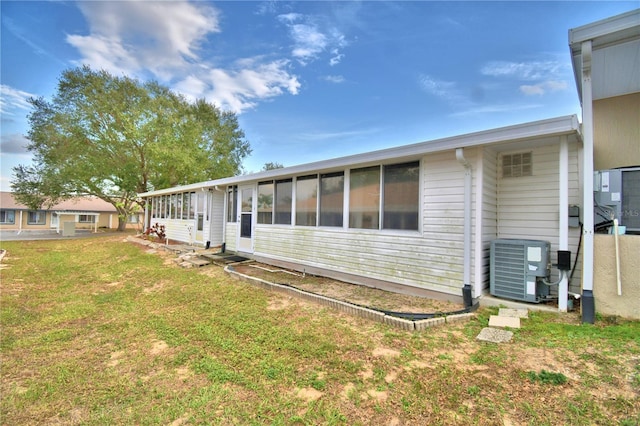 back of house with a sunroom, a yard, and cooling unit