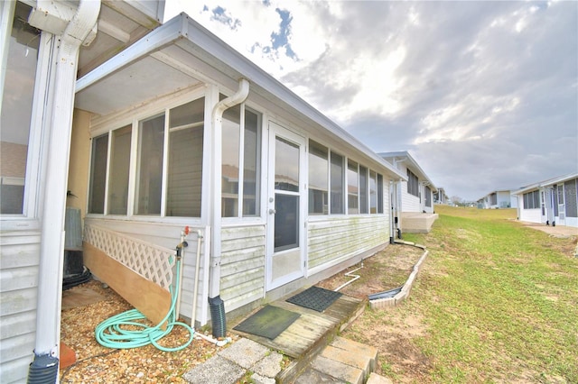 view of home's exterior with a sunroom and a lawn