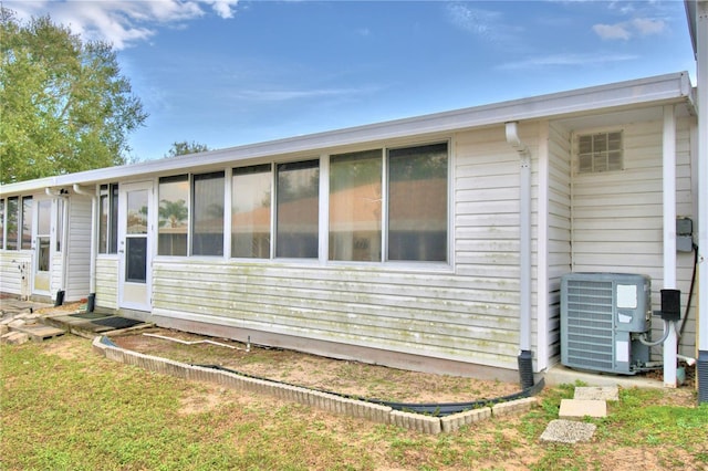 rear view of property featuring a sunroom and central air condition unit