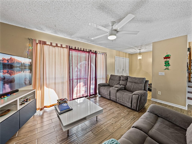 living room featuring ceiling fan and a textured ceiling