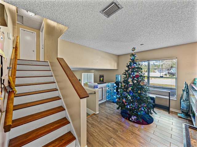 stairs featuring wood-type flooring and a textured ceiling