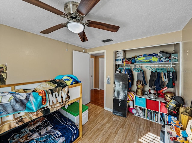 bedroom featuring a textured ceiling, light wood-type flooring, a closet, and ceiling fan