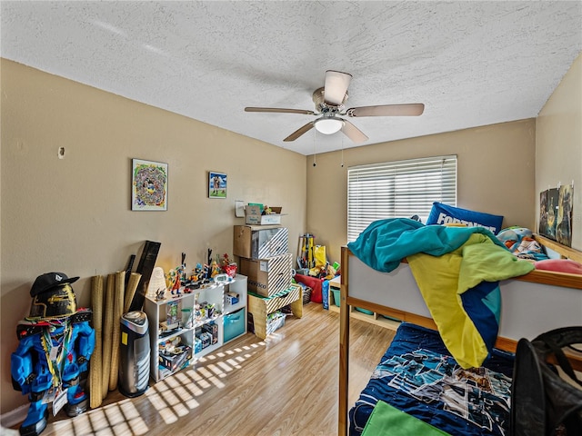 bedroom with hardwood / wood-style flooring, ceiling fan, and a textured ceiling