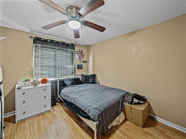 bedroom featuring ceiling fan, light hardwood / wood-style floors, and a textured ceiling