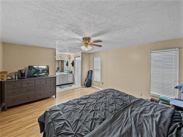 bedroom with a textured ceiling, ensuite bathroom, ceiling fan, and light hardwood / wood-style floors