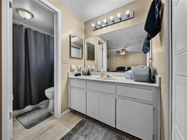 bathroom featuring vanity, a textured ceiling, ceiling fan, hardwood / wood-style floors, and toilet