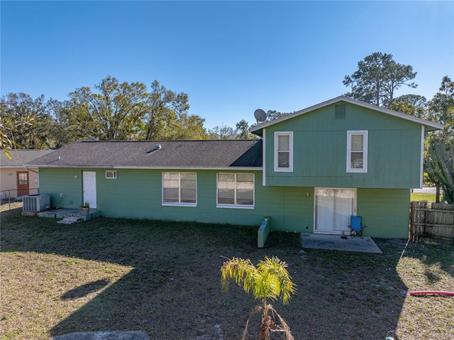 back of property with a yard and central AC