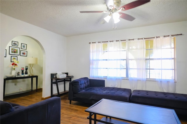 living room featuring hardwood / wood-style floors, ceiling fan, and a textured ceiling