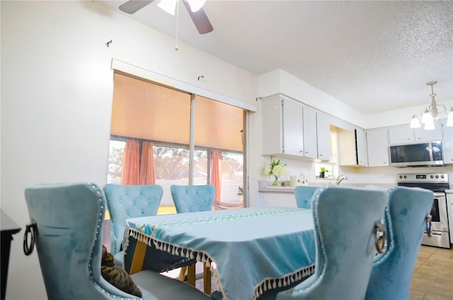 dining area featuring ceiling fan with notable chandelier and a textured ceiling