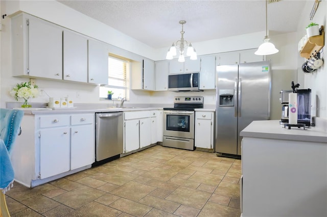 kitchen featuring pendant lighting, an inviting chandelier, white cabinets, a textured ceiling, and stainless steel appliances