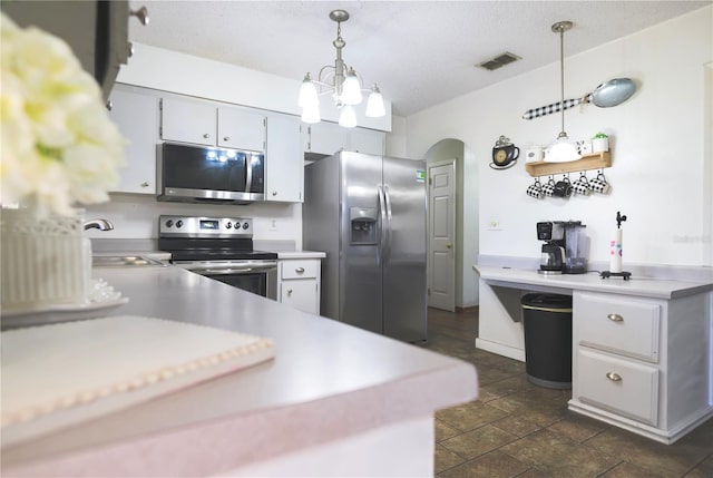 kitchen featuring kitchen peninsula, a textured ceiling, stainless steel appliances, sink, and hanging light fixtures