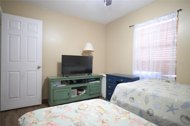 bedroom with a textured ceiling, ceiling fan, and dark wood-type flooring