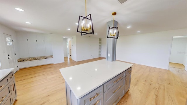 kitchen with a center island, decorative light fixtures, light hardwood / wood-style flooring, gray cabinets, and a notable chandelier