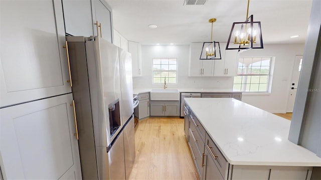 kitchen with gray cabinetry, hanging light fixtures, sink, appliances with stainless steel finishes, and a kitchen island