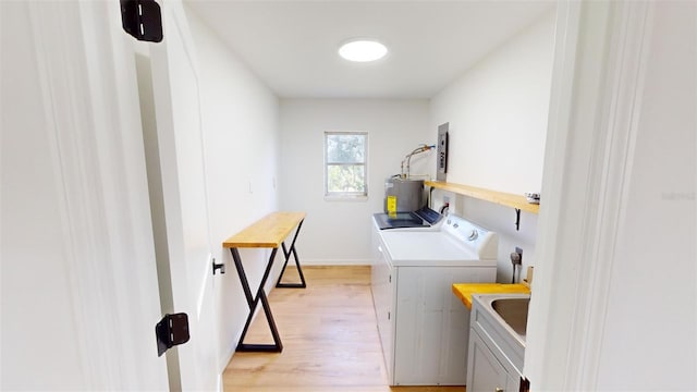 washroom featuring sink, washing machine and dryer, electric water heater, electric panel, and light hardwood / wood-style floors