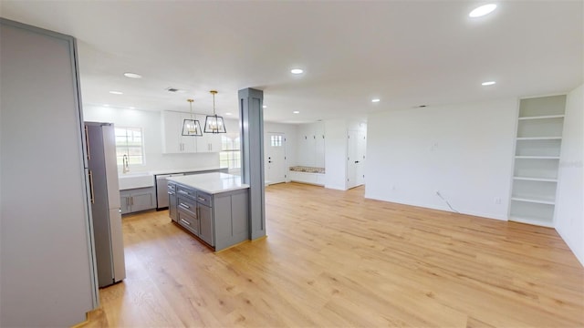 kitchen with light wood-type flooring, gray cabinetry, pendant lighting, dishwasher, and fridge