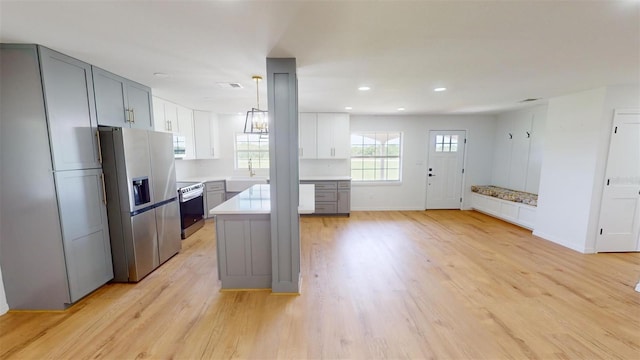 kitchen featuring gray cabinets, stainless steel fridge, light hardwood / wood-style floors, and hanging light fixtures