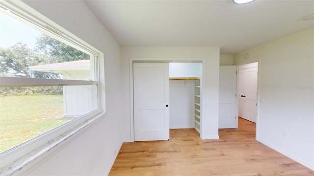 unfurnished bedroom featuring a closet, light wood-type flooring, and multiple windows