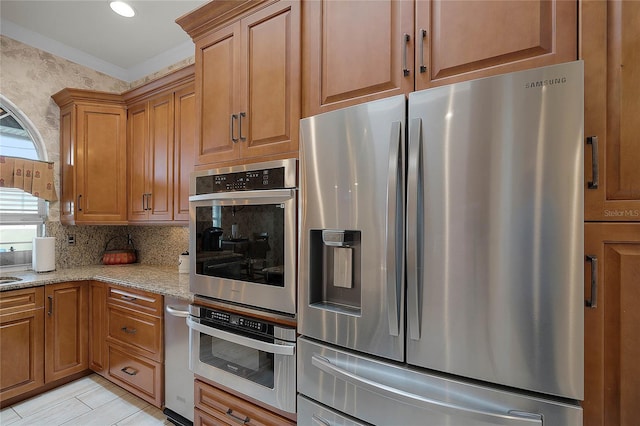 kitchen with light stone countertops, appliances with stainless steel finishes, and tasteful backsplash