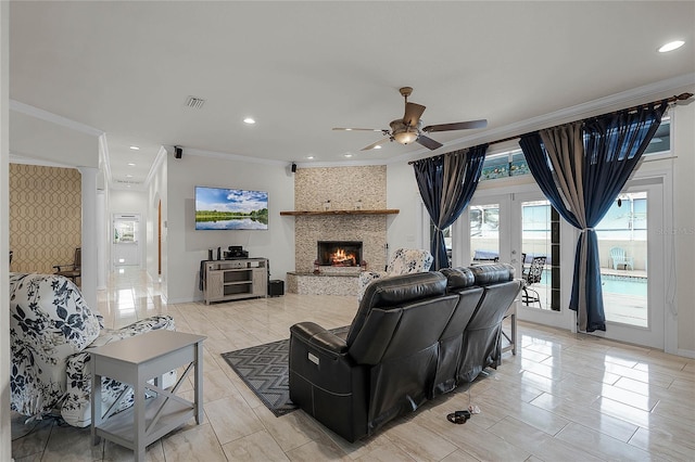 living room with ceiling fan, french doors, a large fireplace, and crown molding