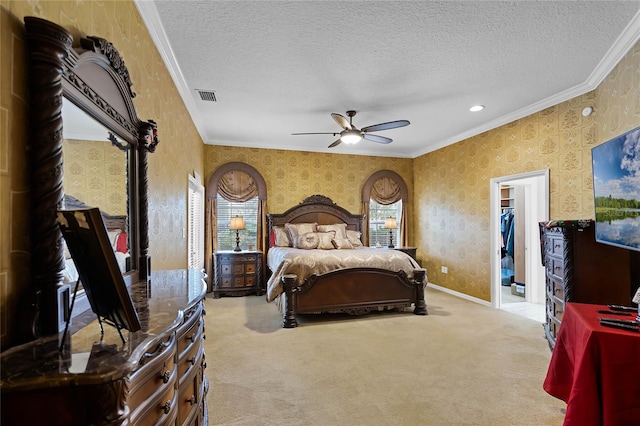 bedroom featuring ceiling fan, light carpet, a spacious closet, and crown molding