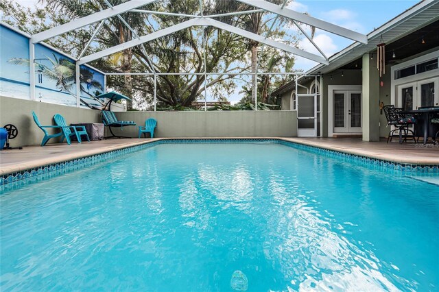 view of swimming pool featuring glass enclosure, a patio area, and french doors