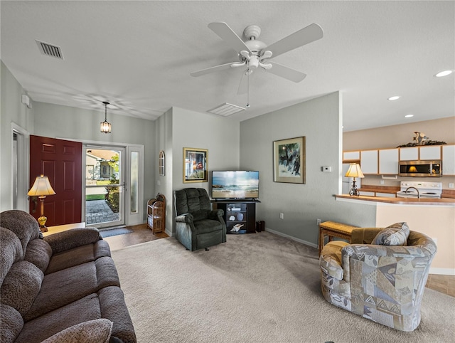 carpeted living room featuring sink and ceiling fan