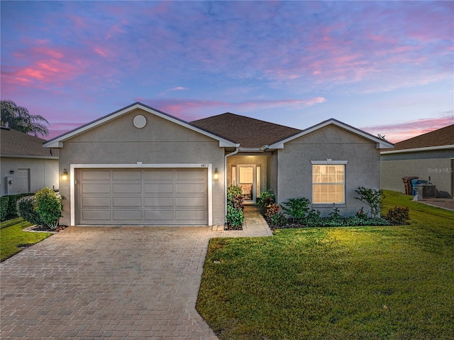 single story home with a garage and a lawn