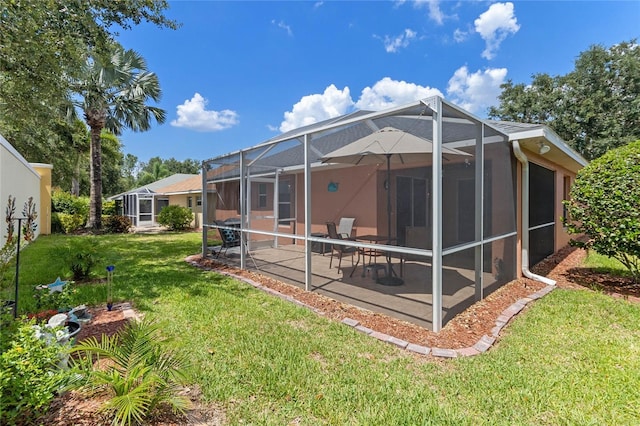 back of house featuring a yard, a patio, and a lanai