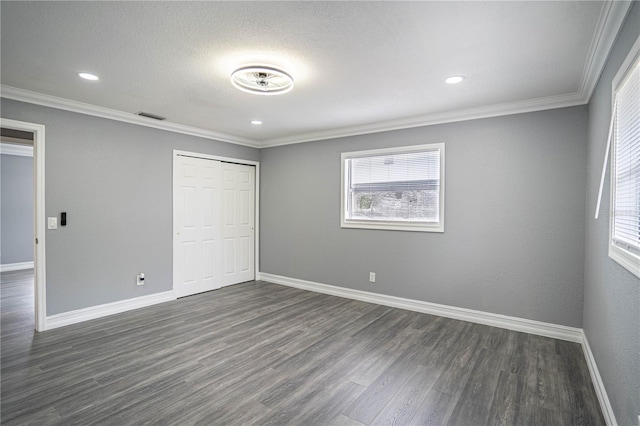 unfurnished bedroom featuring dark hardwood / wood-style floors, ornamental molding, and a closet