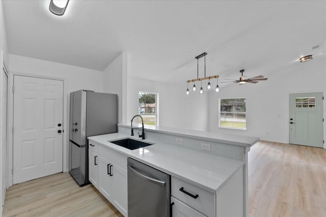 kitchen with sink, a wealth of natural light, appliances with stainless steel finishes, decorative light fixtures, and white cabinetry