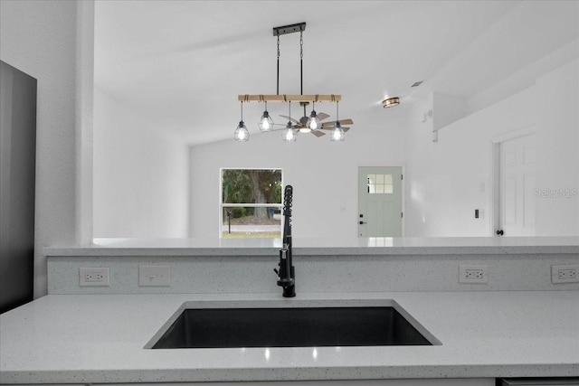 kitchen with light stone countertops, sink, hanging light fixtures, and a notable chandelier