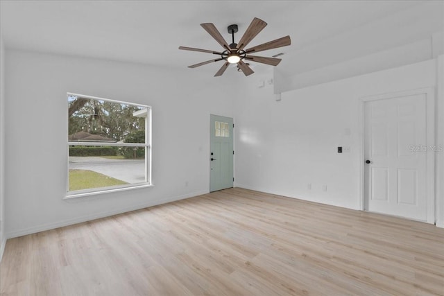 unfurnished living room featuring ceiling fan, light wood-type flooring, and vaulted ceiling