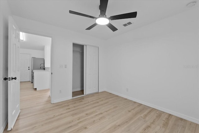 unfurnished bedroom with stainless steel fridge, a closet, ceiling fan, and light hardwood / wood-style floors