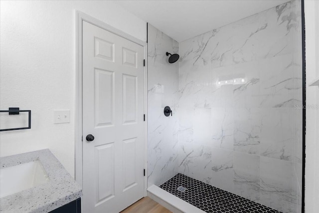 bathroom featuring tiled shower, hardwood / wood-style floors, and vanity