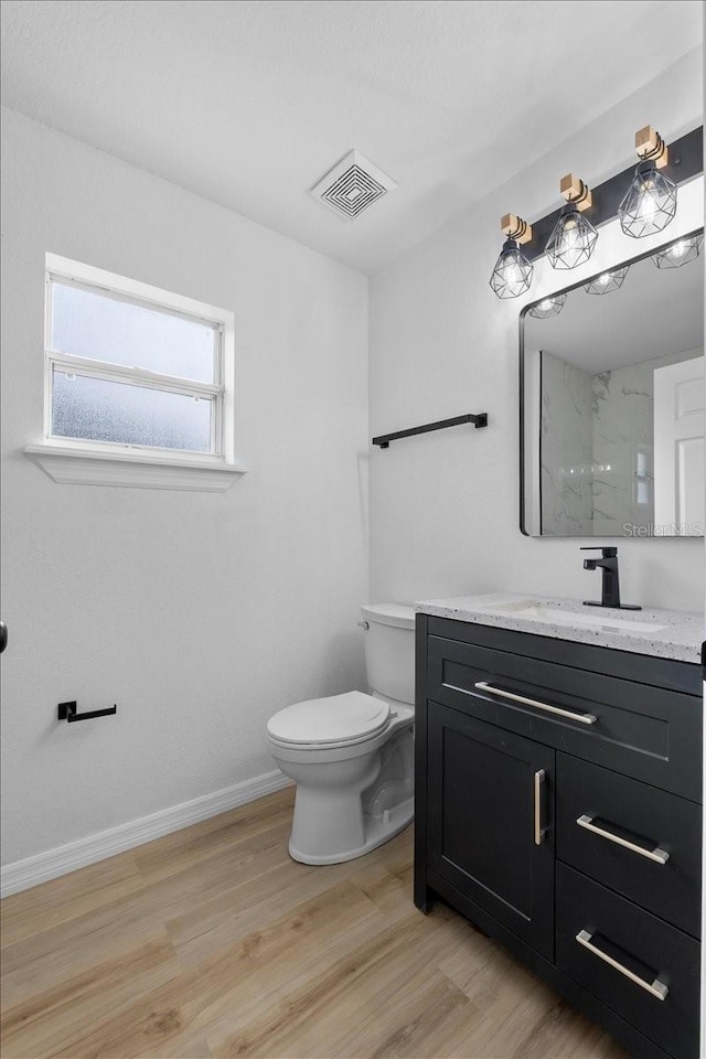 bathroom featuring hardwood / wood-style floors, vanity, toilet, and walk in shower