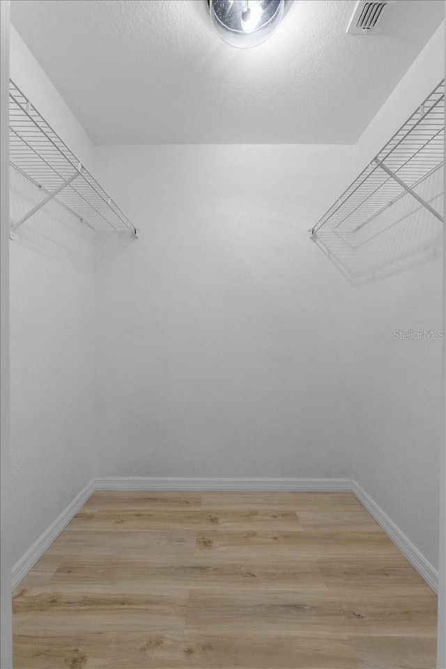 walk in closet with light hardwood / wood-style flooring