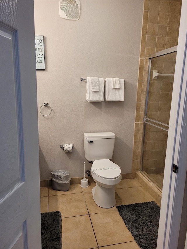 bathroom featuring tile patterned flooring, toilet, and an enclosed shower