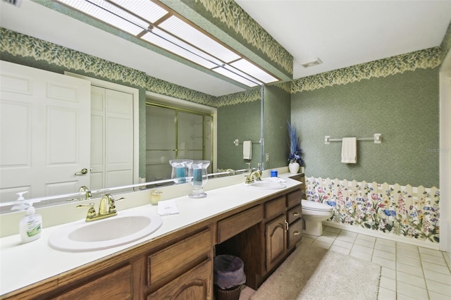 bathroom with toilet, tile patterned flooring, a shower with door, and vanity