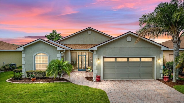 ranch-style house with a garage and a lawn