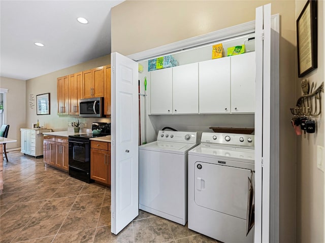 clothes washing area featuring washing machine and dryer and cabinets