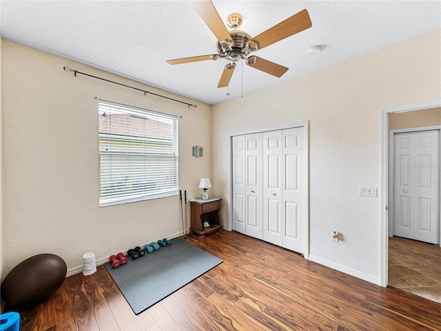 workout room featuring ceiling fan, hardwood / wood-style floors, and a textured ceiling