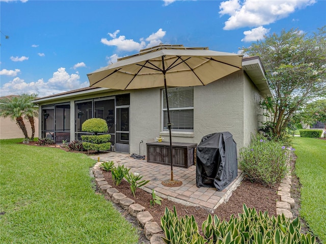 rear view of property with a sunroom, a lawn, and a patio