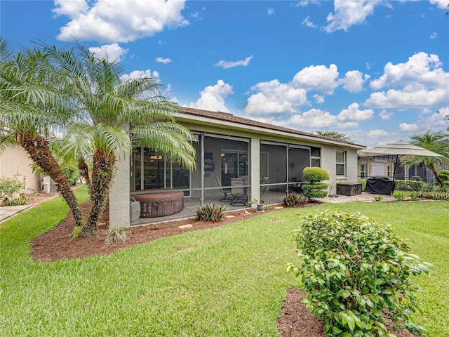 rear view of property with a jacuzzi, a sunroom, a yard, and a patio